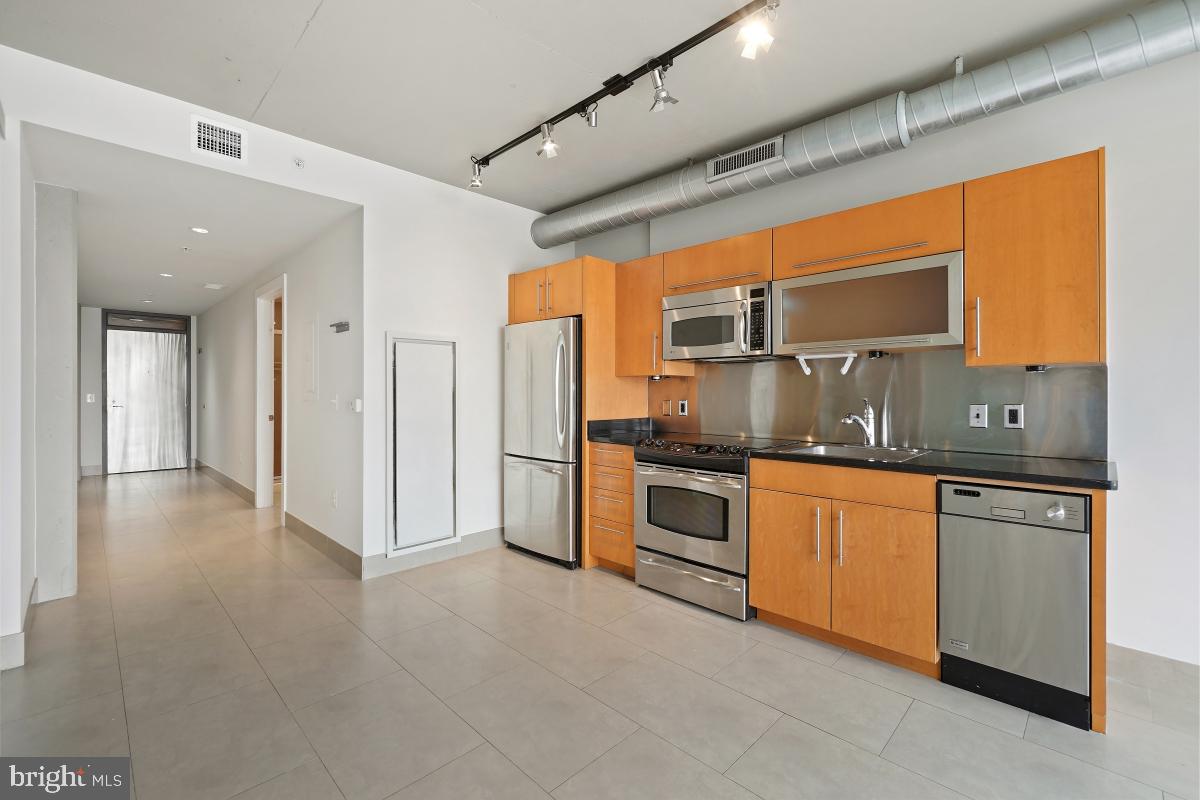 1133 14th Street Northwest, Unit 1103 Washington, DC 20005 - Photo 6 of 39 a kitchen with stainless steel appliances granite countertop a sink and a refrigerator
