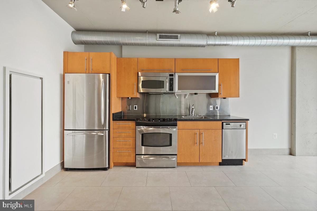 1133 14th Street Northwest, Unit 1103 Washington, DC 20005 - Photo 7 of 39 a kitchen with stainless steel appliances a refrigerator sink and cabinets