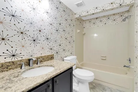 a bathroom with a granite countertop toilet sink and mirror