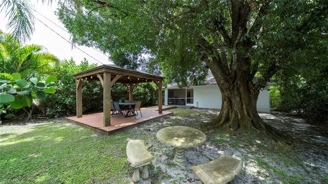 a view of backyard with a table and chairs under an umbrella