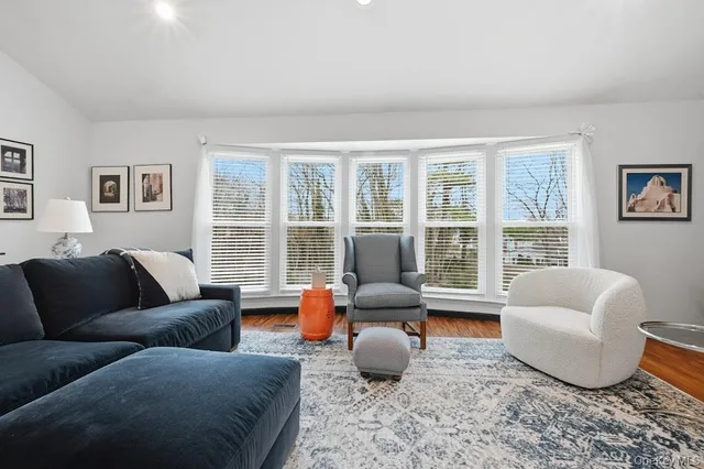 a living room with furniture floor to ceiling window and wooden floor