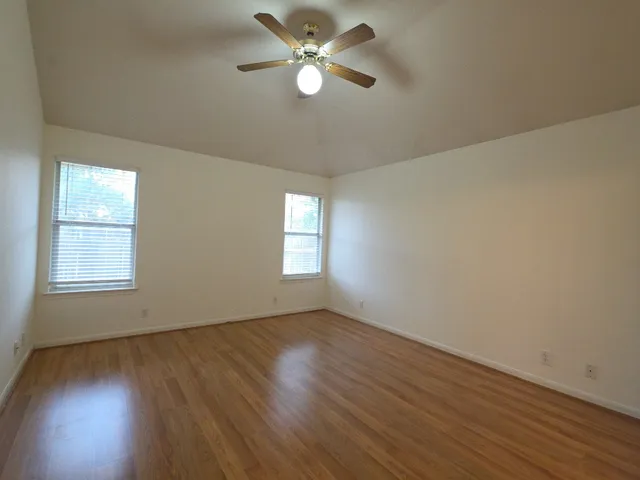 a view of an empty room with window and wooden floor