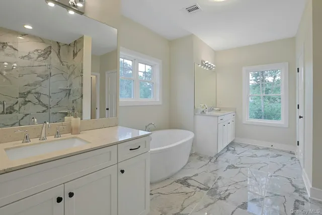 a spacious bathroom with a double vanity sink a mirror and a bathtub
