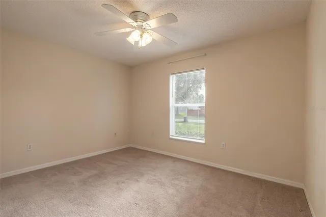 an empty room with a window and a fan