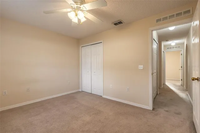 an empty room with closet and a chandelier fan