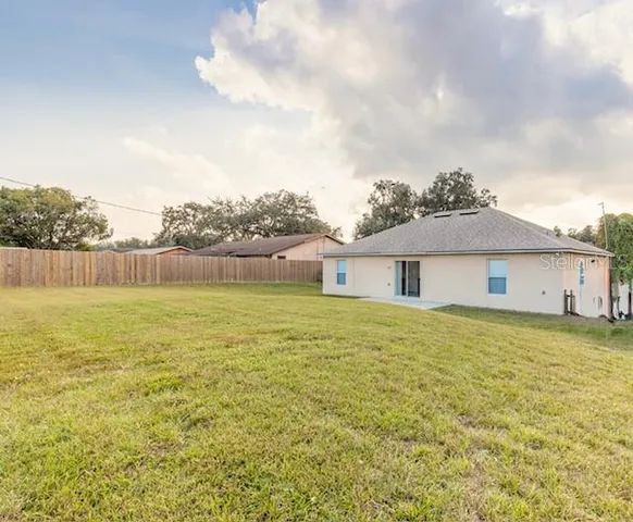 a view of an house with backyard and bushes