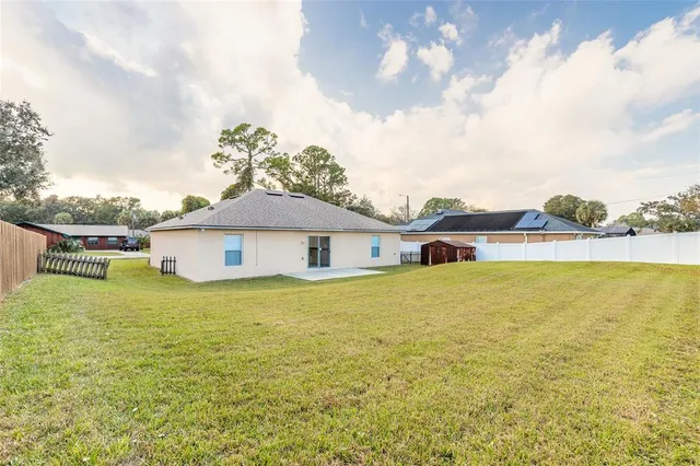 a view of a house with a yard and a large tree
