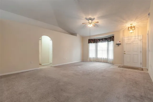 a view of an empty room with a chandelier fan