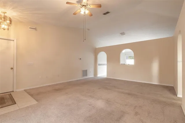 a view of an empty room with a chandelier fan