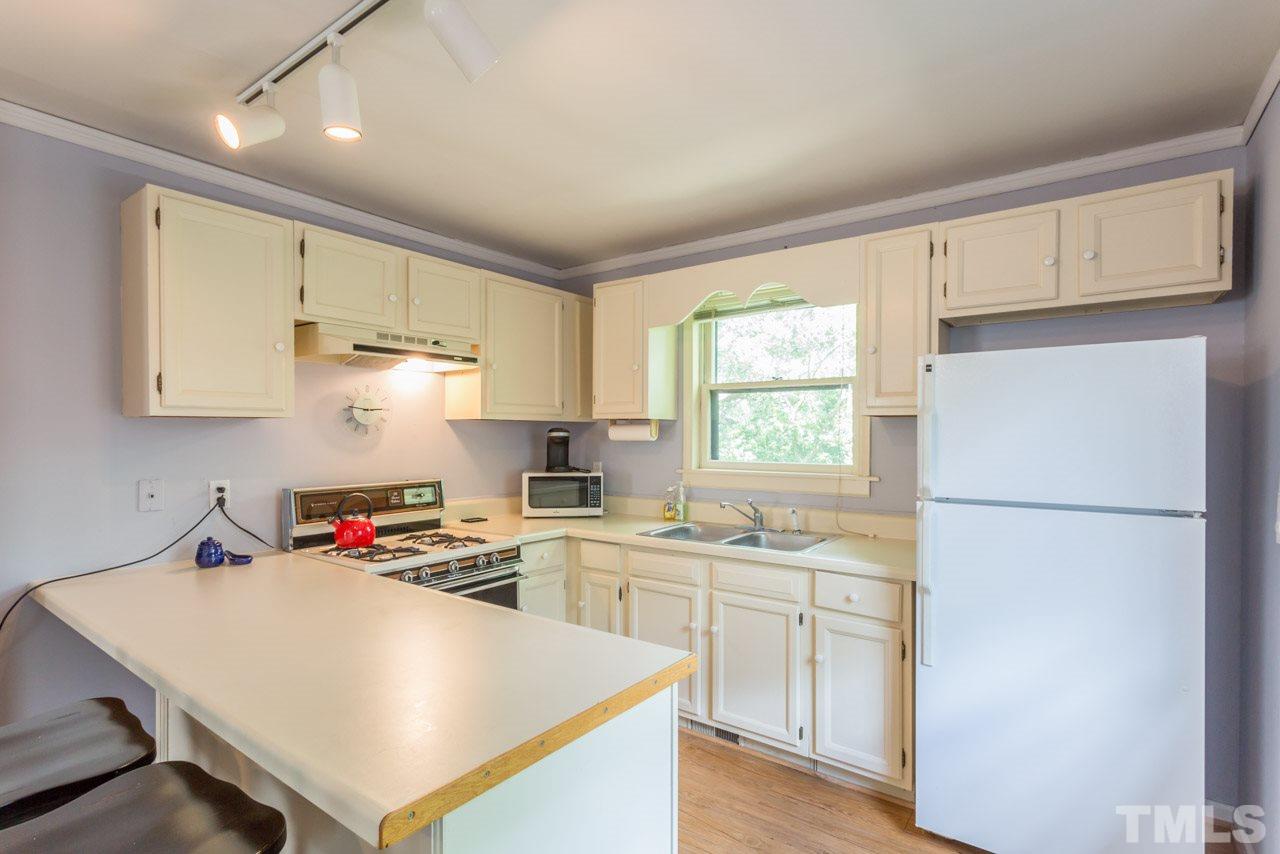 11816 Possum Track Road Raleigh, NC 27614 - Photo 21 of 25 a kitchen with white cabinets and white appliances