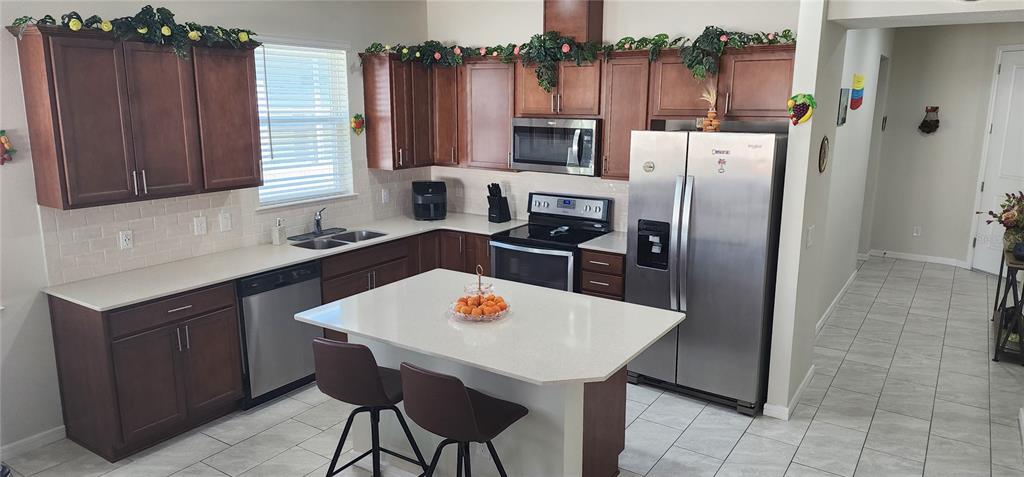 1823 Spring Shower Circle Kissimmee, FL 34744 - Photo 4 of 38 a kitchen with stainless steel appliances a dining table chairs refrigerator and sink