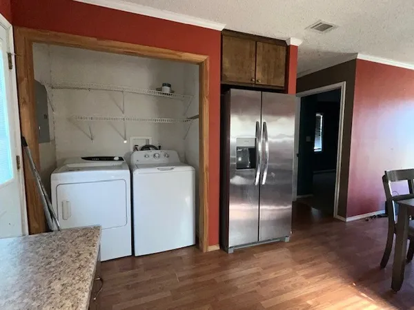 a view of a refrigerator in kitchen and an empty room