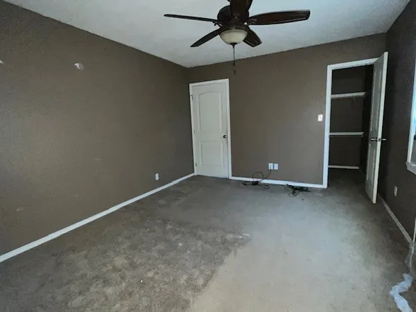 an empty room with a ceiling fan and carpet