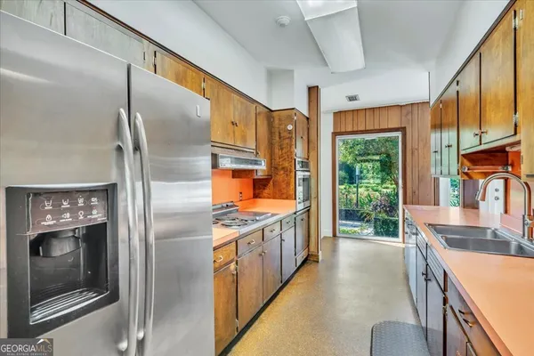 a kitchen with stainless steel appliances granite countertop a refrigerator a sink a stove and a refrigerator