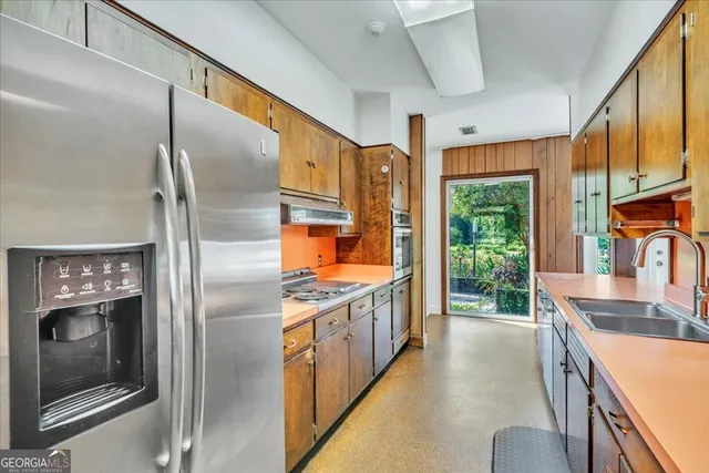 a kitchen with stainless steel appliances granite countertop a refrigerator a sink a stove and a refrigerator