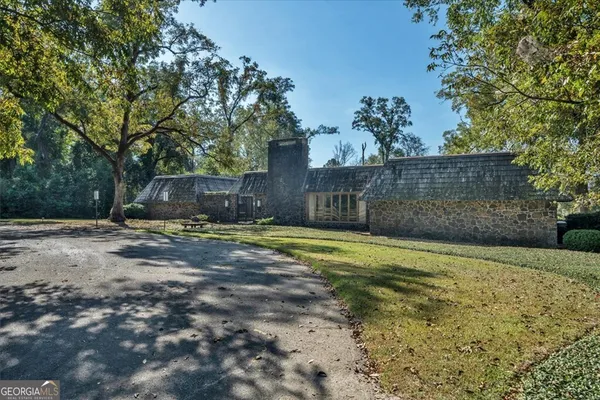a backyard of a house with plants and large trees