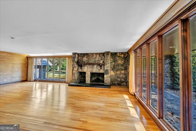 a view of an empty room with wooden floor fireplace and a window