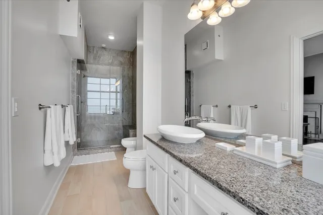 a spacious bathroom with a granite countertop sink a toilet and a large mirror