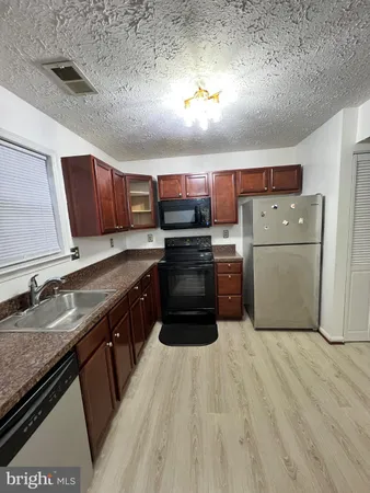 a kitchen with stainless steel appliances granite countertop a refrigerator a stove a sink dishwasher and a microwave oven on the wooden floor