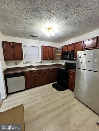 a kitchen with stainless steel appliances granite countertop a refrigerator a sink a stove a microwave and wooden floors