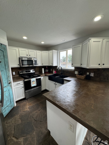 1237 South 260 West Payson, UT 84651 - Photo 36 of 81 Kitchen featuring white shaker-style cabinetry, dark countertops, built-in stainless steel appliances, a black farmhouse sink, and flagstone flooring