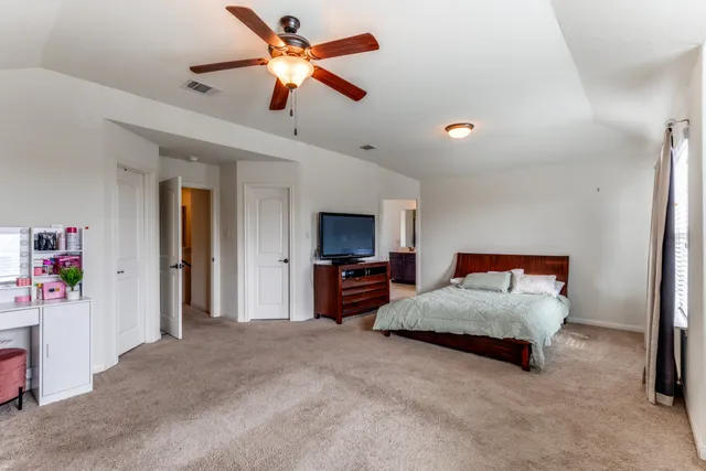 a spacious bedroom with a bed and a flat screen tv