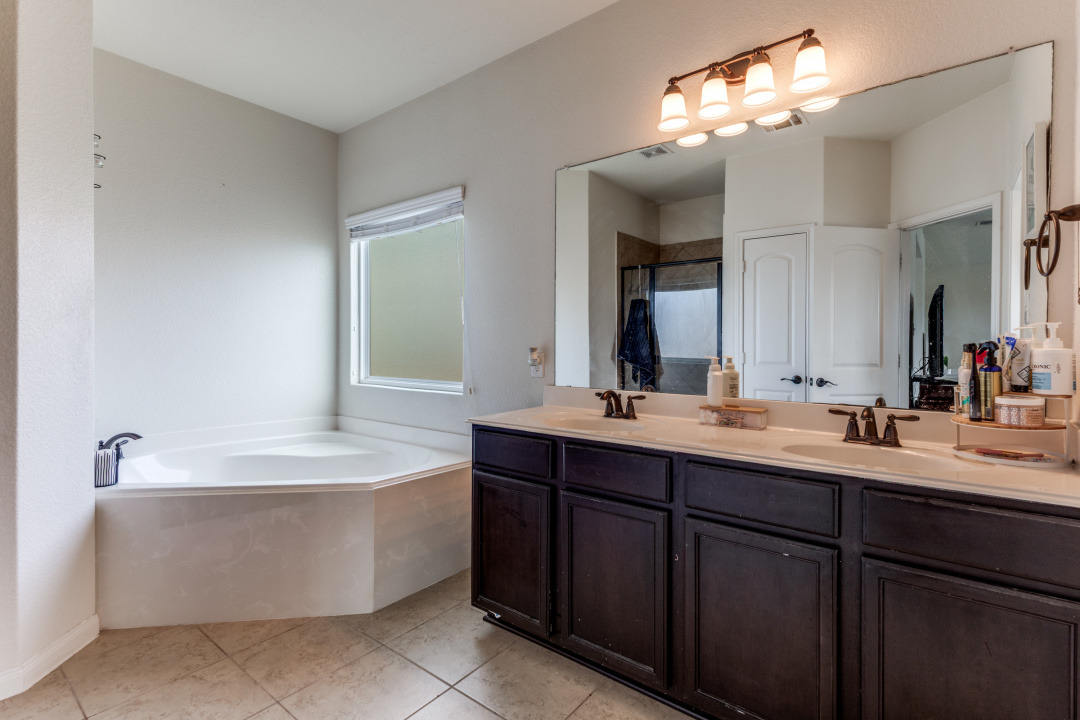 1524 Treeta Trail Kyle, TX 78640 - Photo 15 of 25 a bathroom with a tub a double vanity sink and a mirror