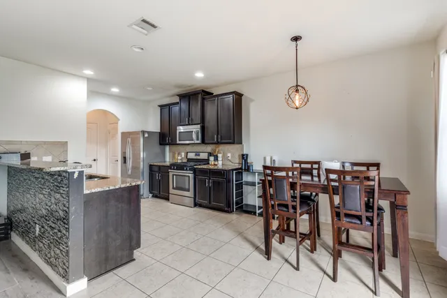 a kitchen with stainless steel appliances kitchen island granite countertop a table chairs and a refrigerator