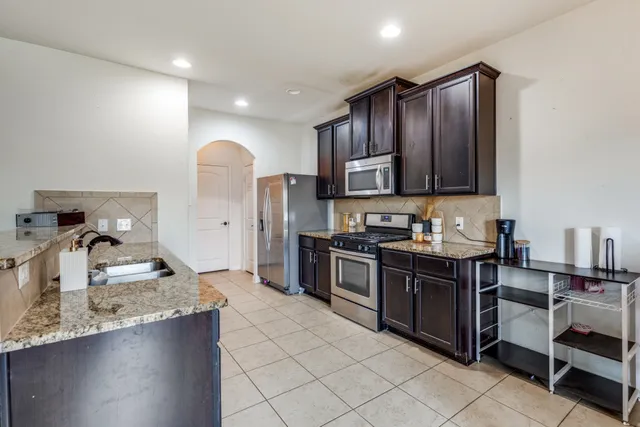 a kitchen with stainless steel appliances granite countertop a sink stove and refrigerator