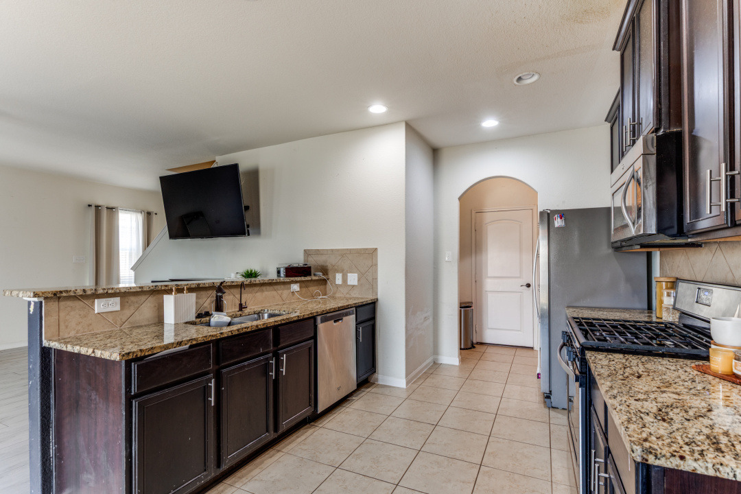 1524 Treeta Trail Kyle, TX 78640 - Photo 9 of 25 a kitchen with granite countertop a sink and a stove top oven with wooden floor