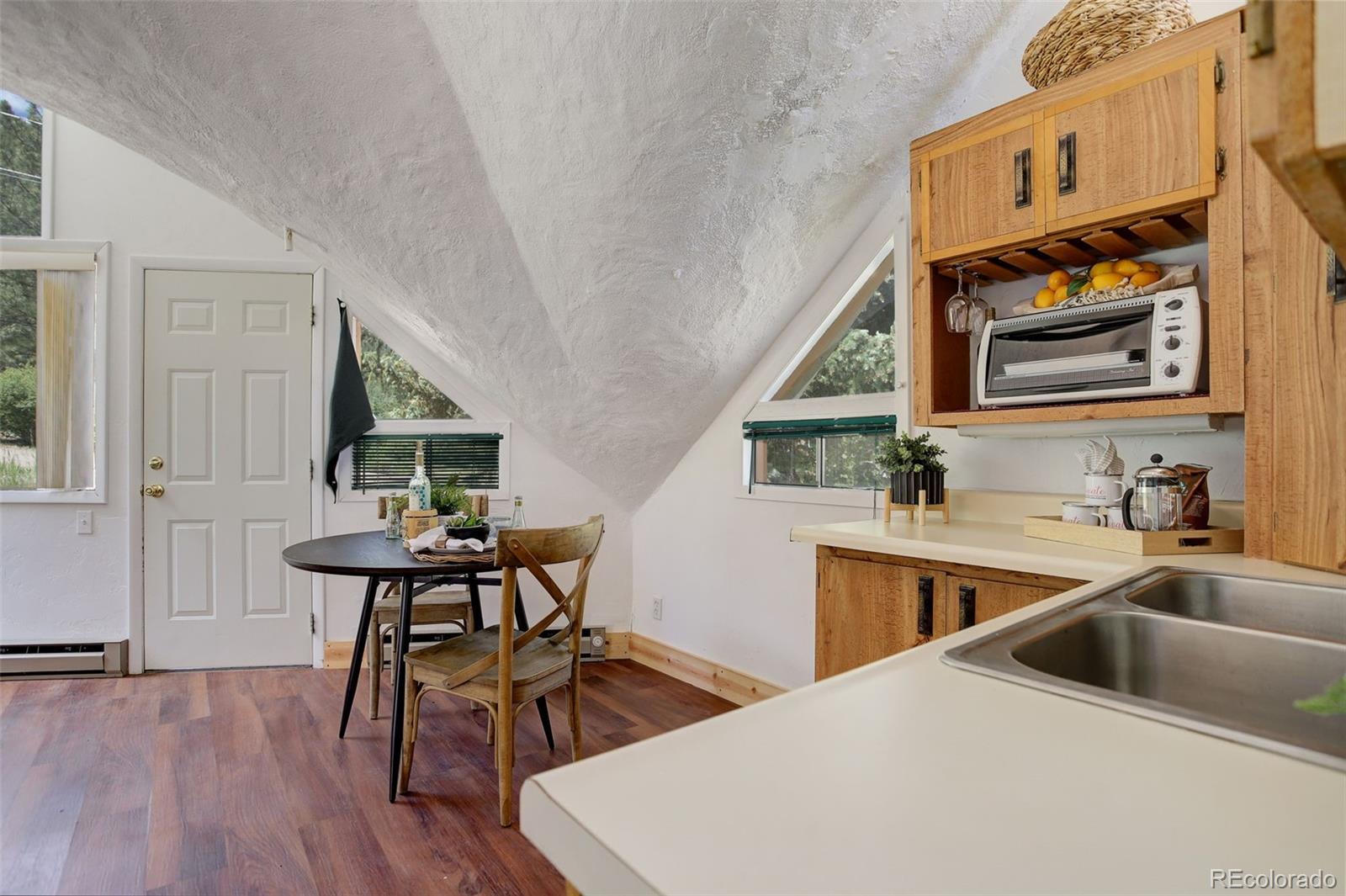 2212 Alvarado Road Georgetown, CO 80444 - Photo 11 of 19 a kitchen with stainless steel appliances a sink a stove a dining table and chairs with wooden floor