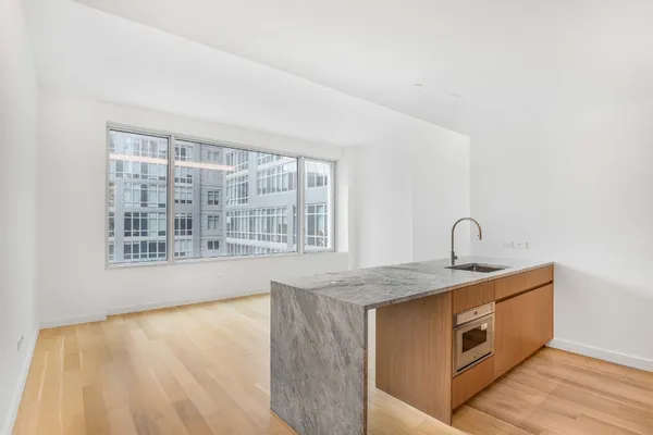 a view of a kitchen with a sink wooden cabinets and a window