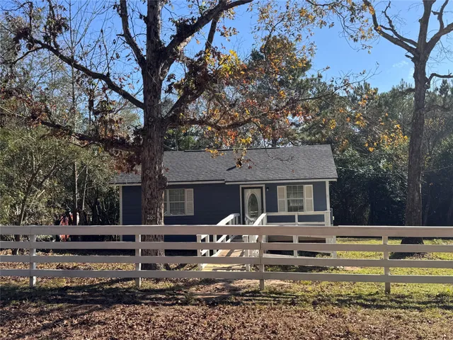 a view of a house with a yard chairs and a tree