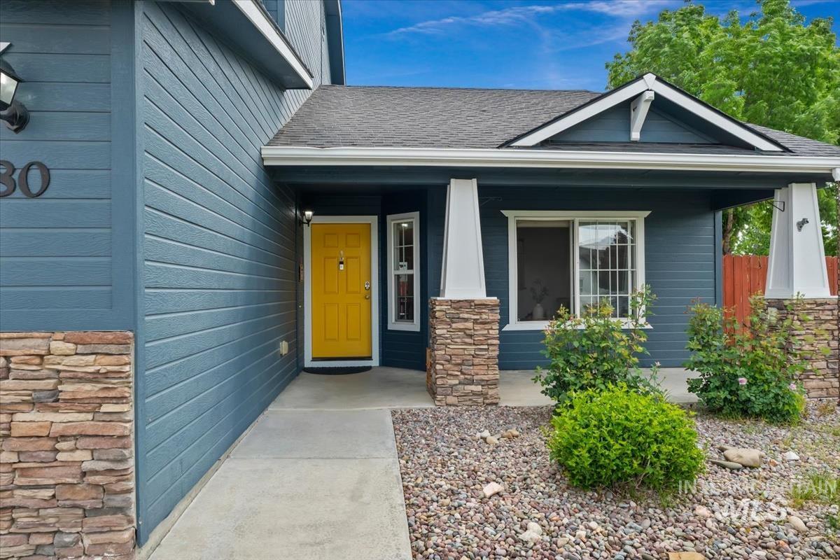80 Cobblestone Court Middleton, ID 83644 - Photo 35 of 48 Welcoming exterior with blue siding, stone veneer accents, a covered front porch, and a vibrant yellow entry door