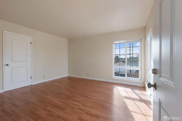 a view of empty room with wooden floor and fan