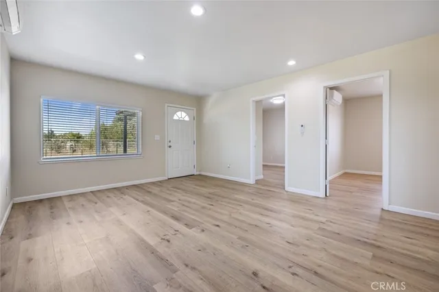 a view of an empty room with wooden floor and window