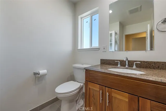 a bathroom with a granite countertop toilet sink and mirror