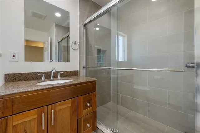 a bathroom with a granite countertop sink a mirror and a shower