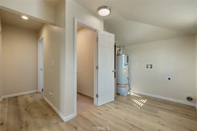 an empty room with wooden floor and entrance to other room