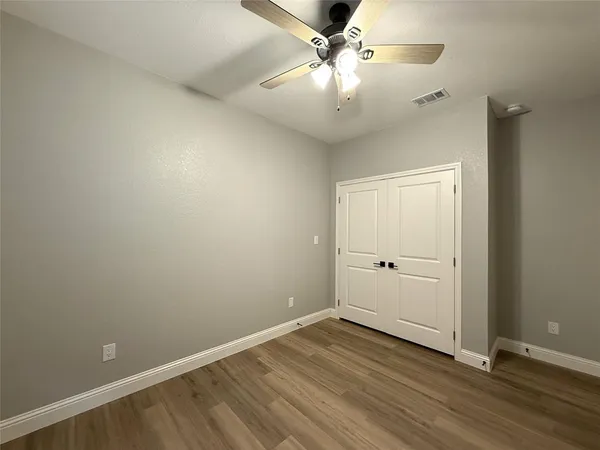 an empty room with wooden floor and ceiling fan