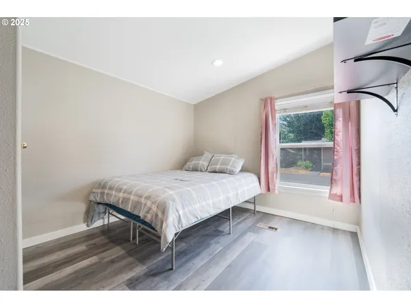 a bedroom with a bed window and wooden floor