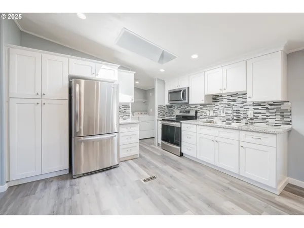 a kitchen with kitchen island white cabinets and stainless steel appliances