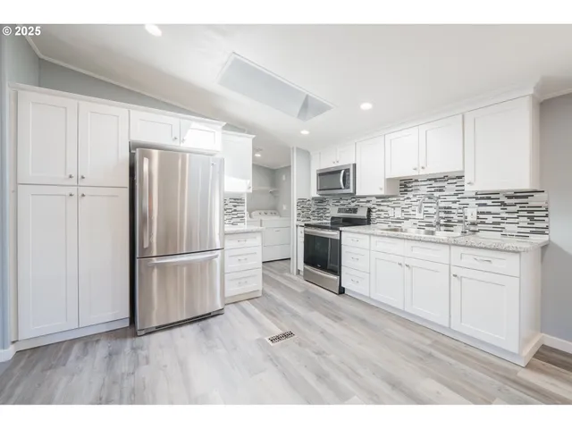 a kitchen with kitchen island white cabinets and stainless steel appliances
