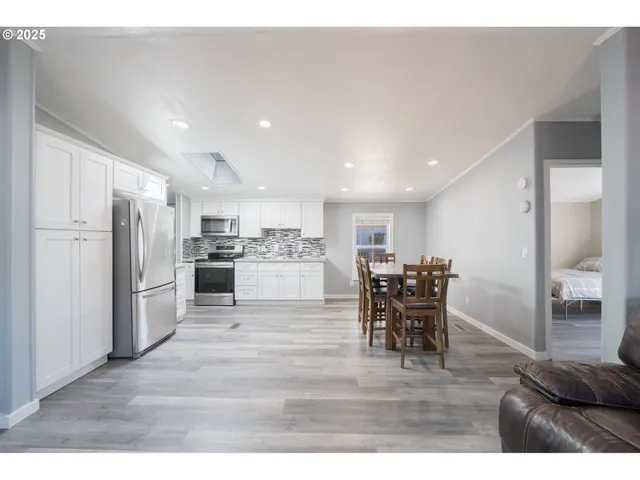 a kitchen with stainless steel appliances kitchen island granite countertop a refrigerator and a dining table