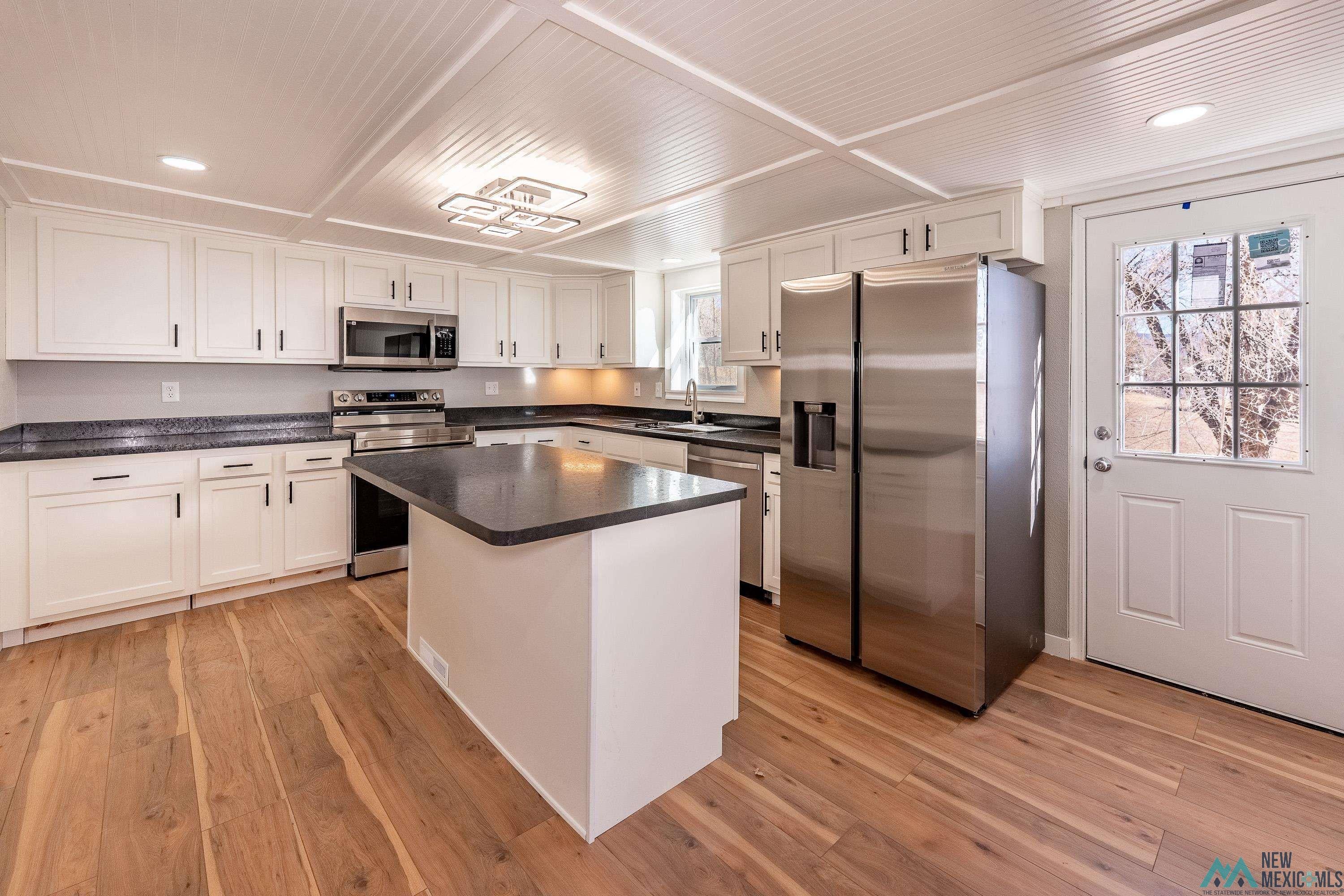 1131 Lincoln Avenue Raton, NM 87740 - Photo 5 of 41 Kitchen with appliances with stainless steel finishes, white cabinets, light wood-style flooring, a center island, and recessed lighting