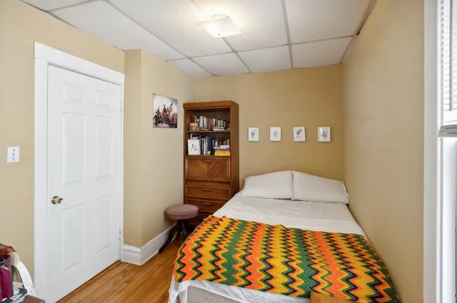 a view of a hallway with wooden floor and a bathroom
