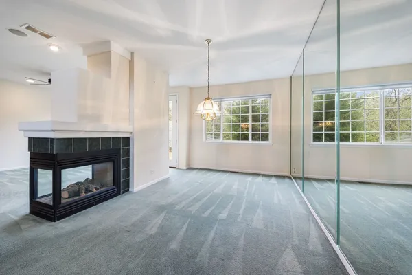 a view of an empty room with a window and fireplace