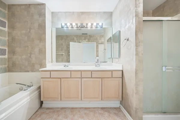 a bathroom with a double vanity sink a mirror and a bathtub