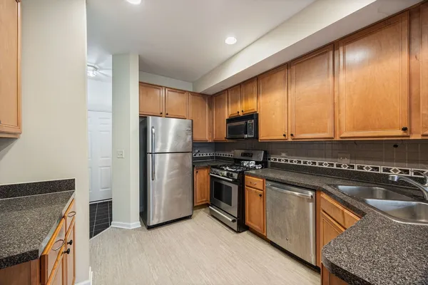a kitchen with stainless steel appliances granite countertop a refrigerator a stove a sink and a microwave