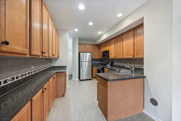 a kitchen with stainless steel appliances granite countertop a stove a refrigerator and a sink